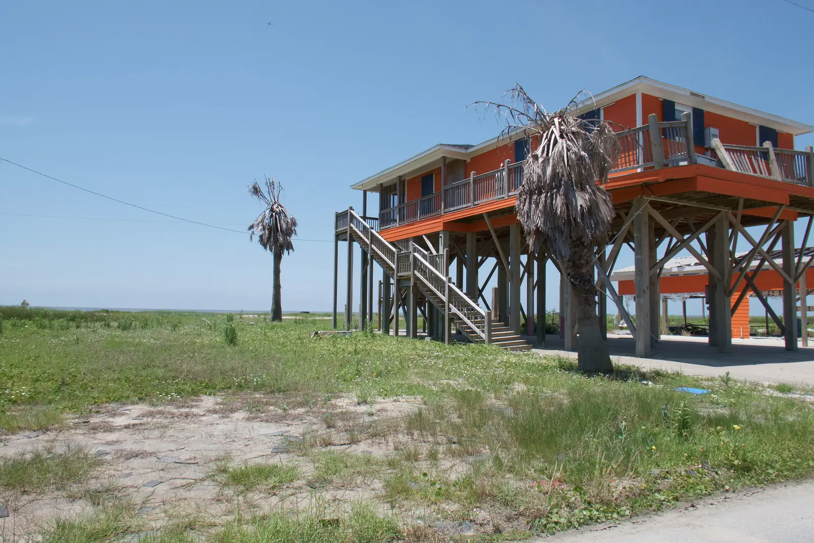 An orange house raised on tall wooden pilings in Holly Beach, Louisiana