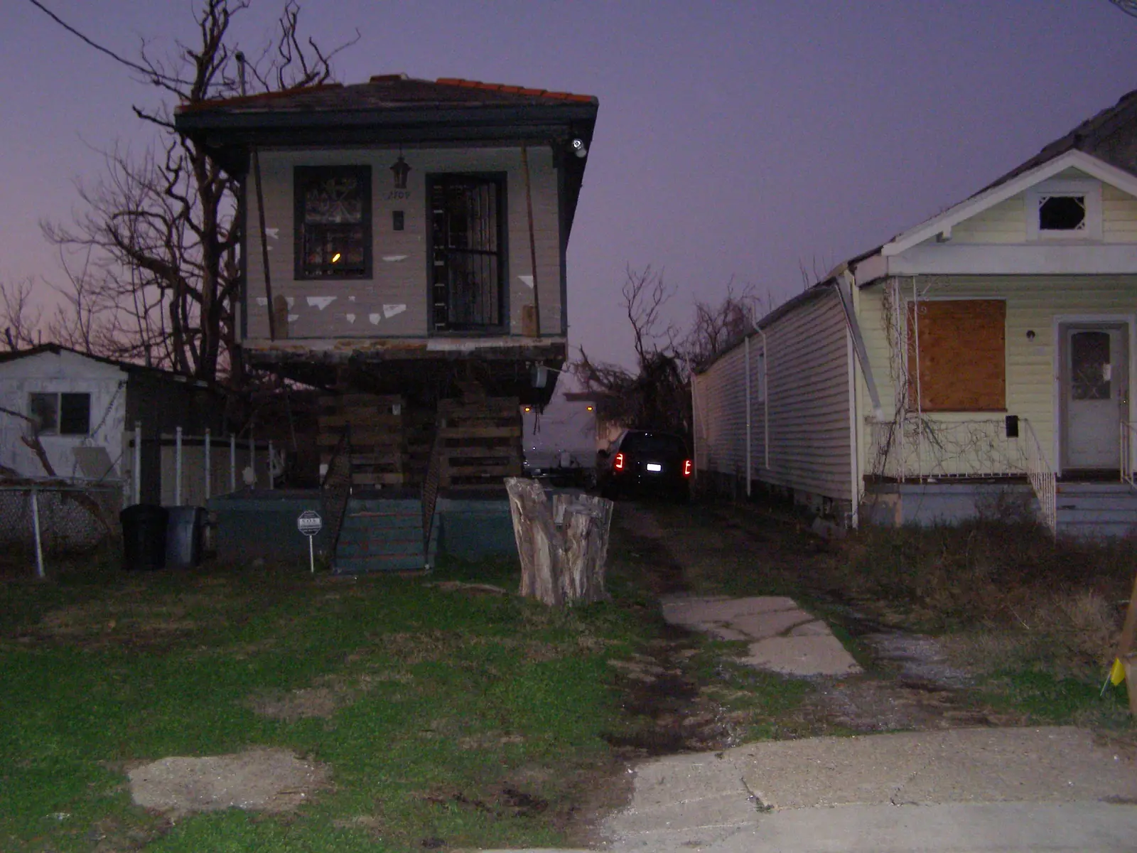 A flood-damaged house held up on stacked timber cribbing during its elevation